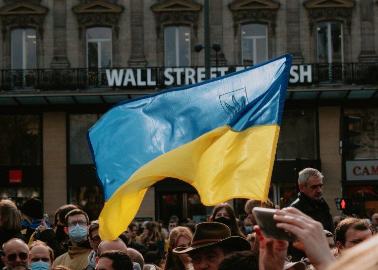 blue and yellow ukrainian flag waving above crowd of people
