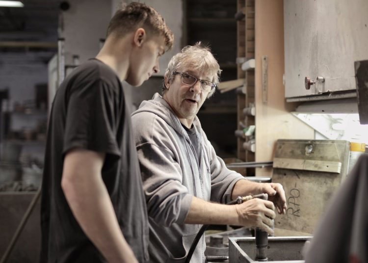 workers handling detail by pneumatic tool in workshop