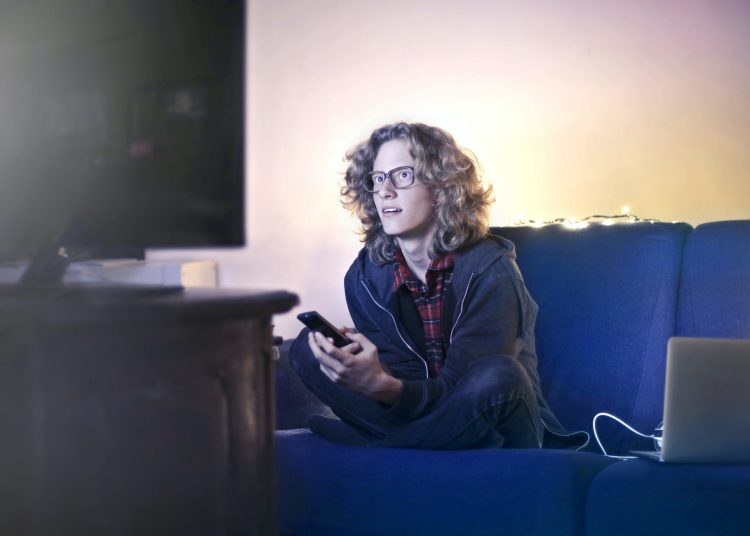 young man using smartphone and watching tv in living room