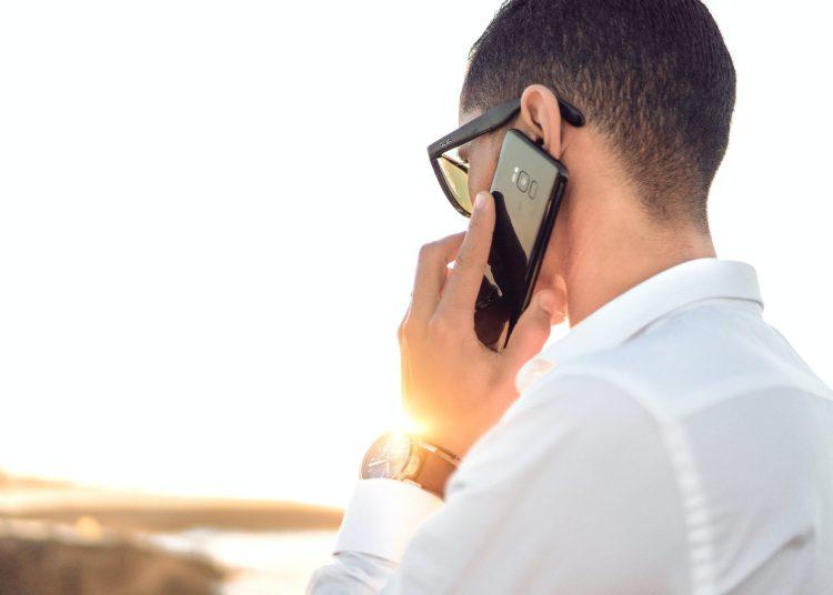 shallow focus photography of a man in white collared dress shirt talking to the phone using black android smartphone