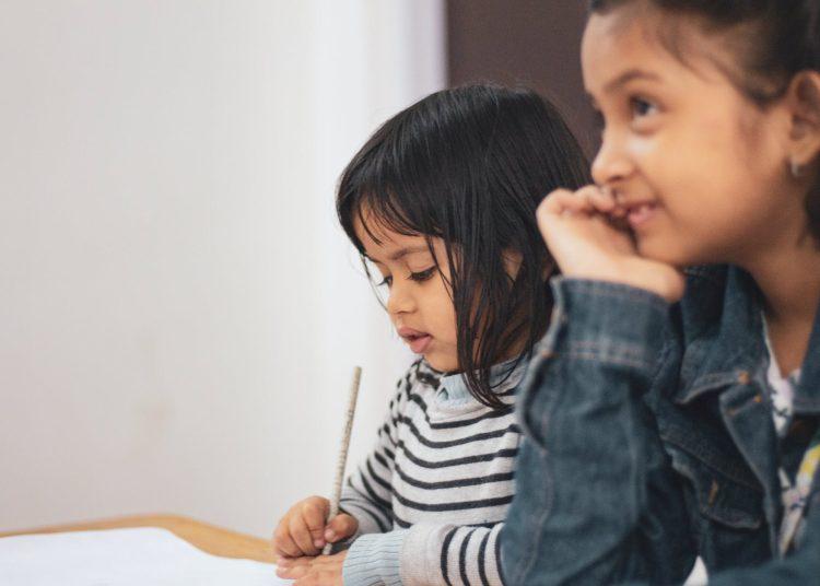 two girls writing on paper