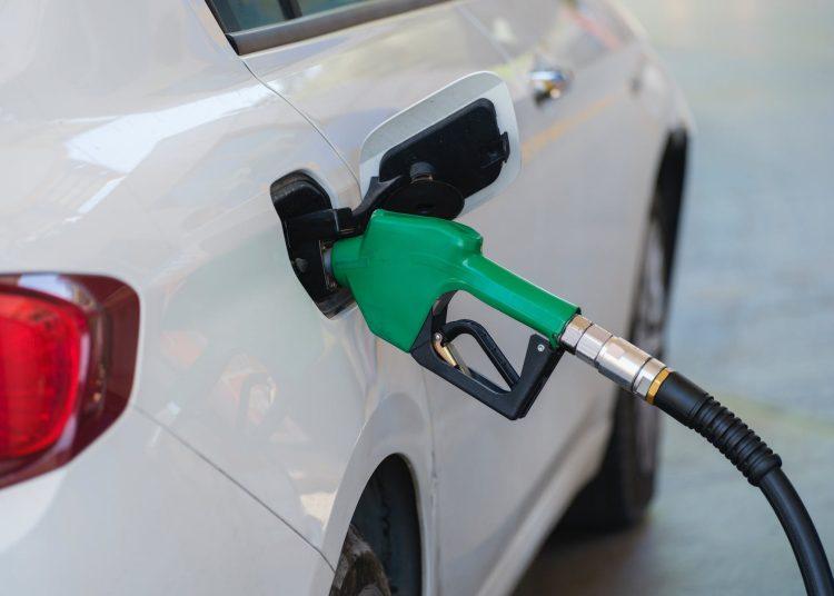 gas pump nozzle filling the white car