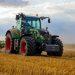green tractor plowing the fields on focus photography