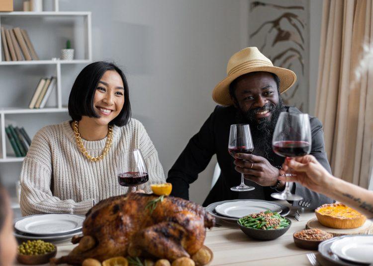 positive multiethnic couple drinking wine with guests