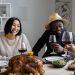 positive multiethnic couple drinking wine with guests